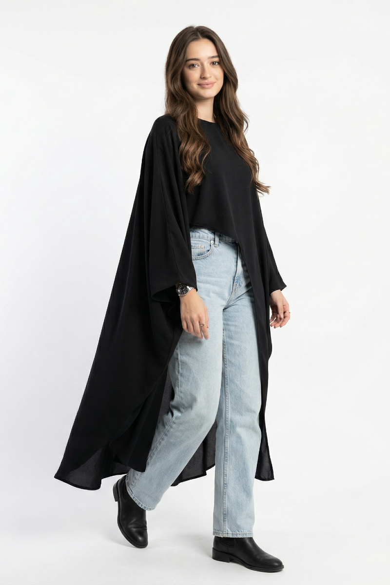 Woman wearing a black long-sleeve top and light blue jeans on a white background