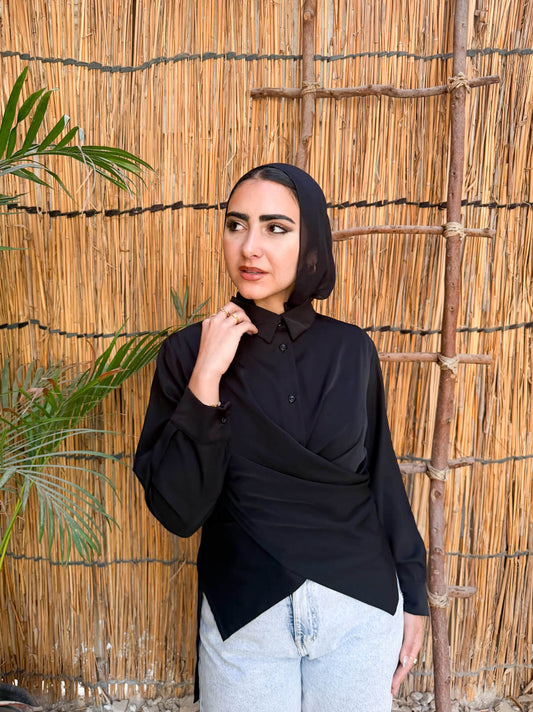 Woman wearing a black hijab and black top against a rustic wooden background