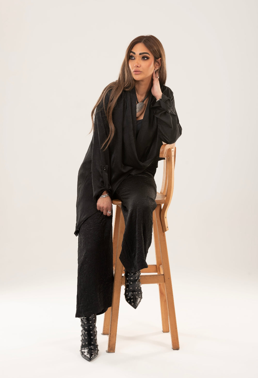 A woman wearing a beige wrap top with long sleeves and matching wide-leg trousers, standing against a neutral background.