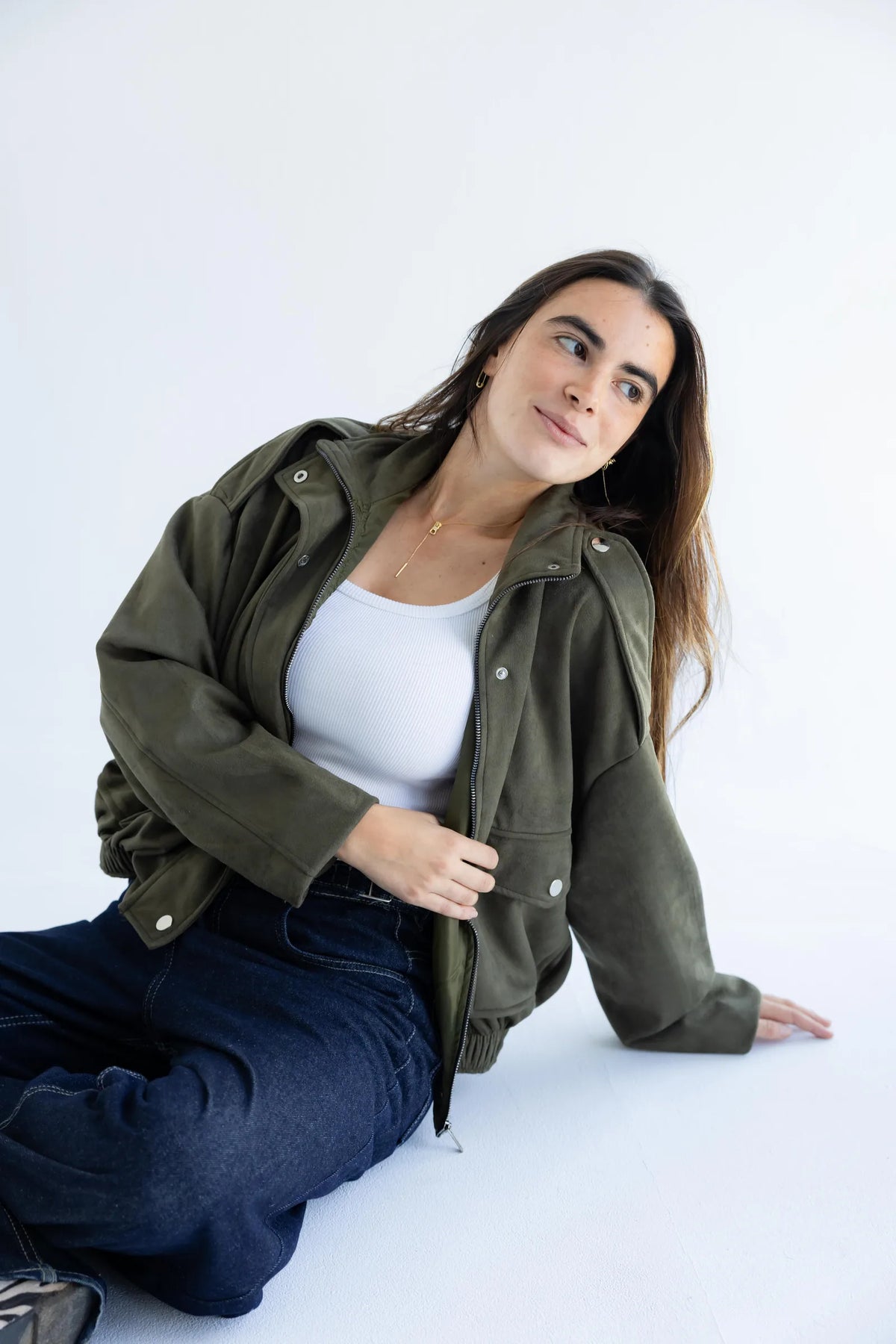Olive green bomber jacket worn open over a white tank
